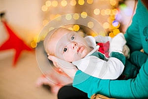 Beautiful young mother with red hair  holds a baby in her arms at home in a room decorated with Christmas garlands, needles.