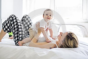 Beautiful young mother and son lying together on a bed