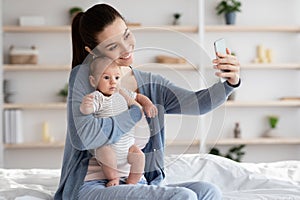 Beautiful Young Mother Taking Selfie With Her Adorable Newborn Baby At Home