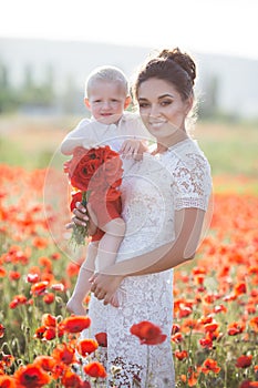 A happy mother with a small son in her arms on the endless field of red poppies on a sunny summer day photo