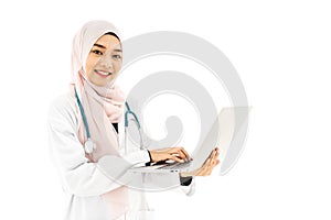 Beautiful young muslim woman doctor wearing doctor uniform and Hijab and Stethoscope using digital laptop computer