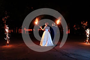 Beautiful young newlywed couple with fire torches in their hands and fireworks 1