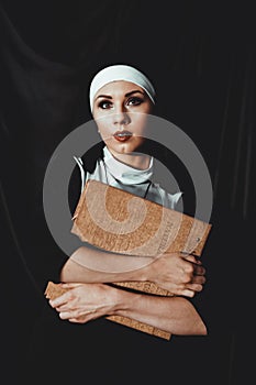 Beautiful young nun in religion black suit holds Bible. Religion concept