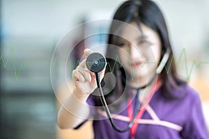 Beautiful young nurse holding stethoscope and listening to gree