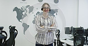 Beautiful young operator woman standing and wearing headset at the bright office space