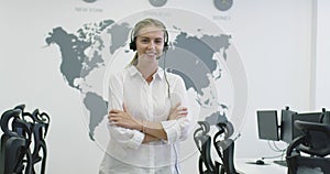 Beautiful young operator woman standing and wearing headset at the bright office space