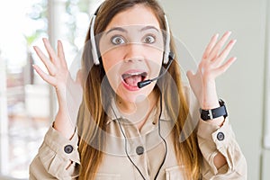 Beautiful young operator woman wearing headset at the office celebrating crazy and amazed for success with arms raised and open