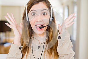 Beautiful young operator woman wearing headset at the office celebrating crazy and amazed for success with arms raised and open