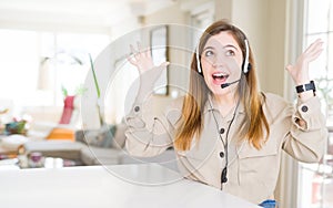 Beautiful young operator woman wearing headset at the office celebrating crazy and amazed for success with arms raised and open