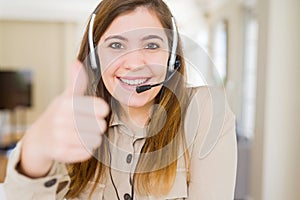 Beautiful young operator woman wearing headset at the office doing happy thumbs up gesture with hand