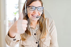 Beautiful young operator woman wearing headset at the office doing happy thumbs up gesture with hand