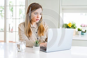 Beautiful young operator woman working with laptop and wearing headseat scared in shock with a surprise face, afraid and excited