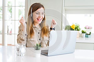 Beautiful young operator woman working with laptop and wearing headseat screaming proud and celebrating victory and success very