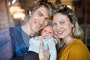 Beautiful young parents with a newborn baby at home. Shot through glass.