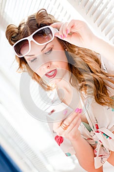 Beautiful young pinup girl having fun reading message on mobile cell phone and wearing sunglasses closeup portrait picture