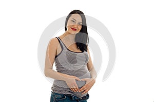 Beautiful young pregnant brunette woman touching her belly and looking at the camera isolated on white background
