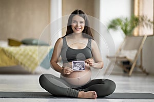 Beautiful young pregnant female demonstrating her baby sonography photo