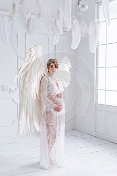 Beautiful young pregnant girl with big angel wings