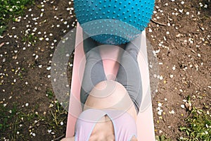 Beautiful young pregnant woman doing exercising with fitness pilates blue ball in park outdoor. Sitting and relaxing on pink yoga