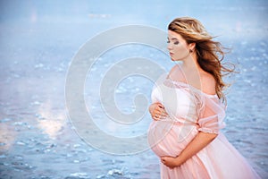 Beautiful young pregnant woman enjoying the sun on pink lake