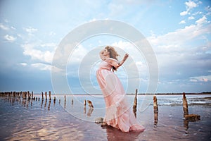 Beautiful young pregnant woman enjoying the sun on pink lake