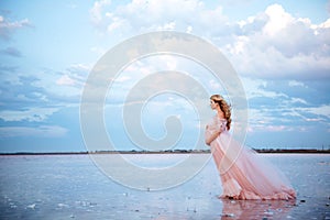 Beautiful young pregnant woman enjoying the sun on pink lake