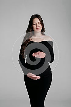 beautiful young pregnant woman on gray background in a photo studio