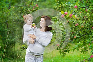 Beautiful young pregnant woman and her laughing baby daughter