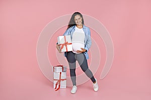 Beautiful young pregnant woman posing with wrapped gift boxes
