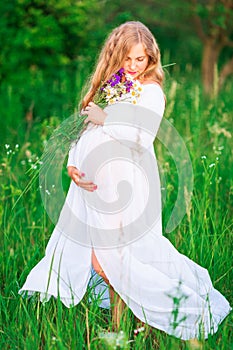 Beautiful young pregnant woman relaxing in nature on a beautiful sunny day