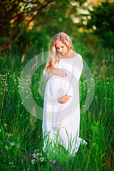 Beautiful young pregnant woman relaxing in nature on a beautiful sunny day