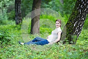 Beautiful young pregnant woman relaxing in a park