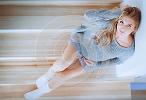 Beautiful young pregnant woman sits on the steps of a wooden ladder
