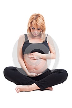 Beautiful young pregnant woman sitting with crossed legs