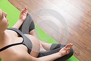 Beautiful young pregnant woman sitting on mat in yoga pose at the home. Pregnancy Yoga and Fitness concept at coronavirus time