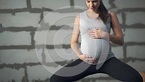 Beautiful young pregnant woman stroking her belly.