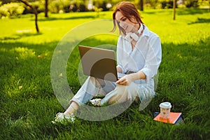 Beautiful young pretty redhead woman in park outdoors using laptop computer for study or work