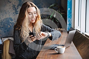 Beautiful young pretty woman sitting in cafe indoors using laptop computer and mobile phone