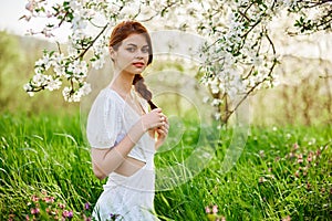 beautiful young readhead woman standing near the apple tree