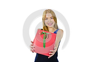 A beautiful young red-haired girl in an evening dress who holds a gift in a red box with both hands intending to present