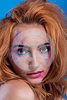 Beautiful young red-haired girl with a spray of paint on her face