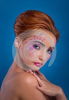 Beautiful young red-haired girl with a spray of paint on her face