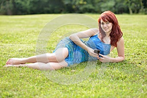 Beautiful young red haired woman outside in summer listens to music