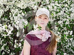 Beautiful young redhead woman in blossoming garden. Close up portrait.