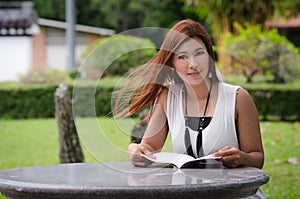 Beautiful young redhead woman reading outdoors