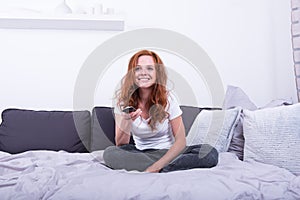 Beautiful, young, redheaded woman is enjoying the TV program