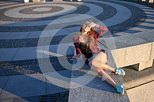 Beautiful young redheaded woman sitting on waterfront, enjoying nature and the good weather. The girl in red plaid shirt