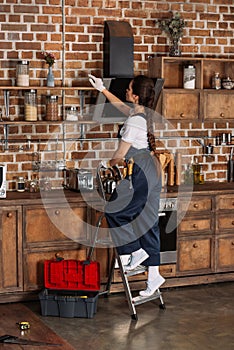 beautiful young repairwoman standing on stepladder