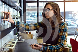 Beautiful young saleswoman doing inventory in a retail store selling coffee.