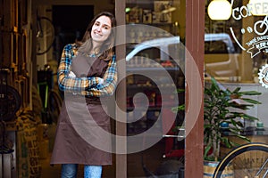 Beautiful young saleswoman looking at camera and leaning against the door frame of an organic store.